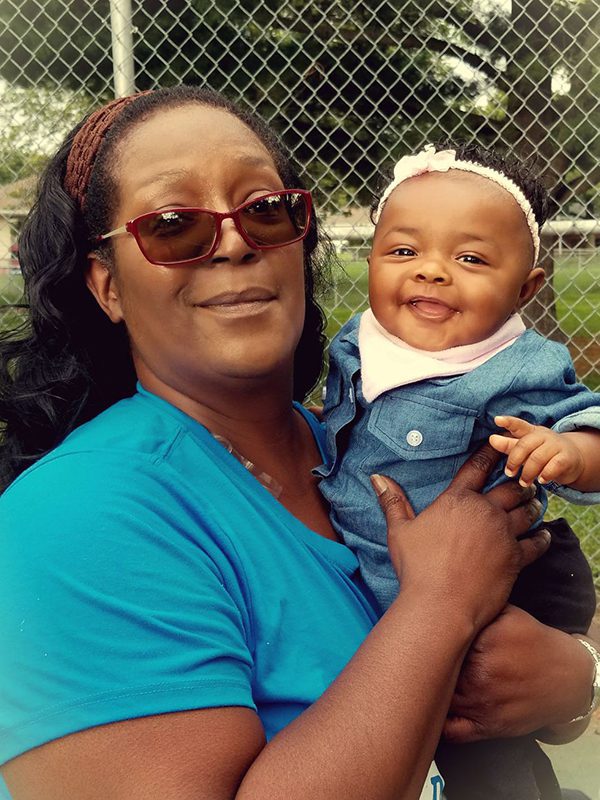 female in blue shirt holding a smiling baby